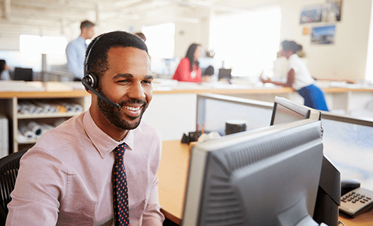smiling-male-call-centre-worker-looking-at-screen